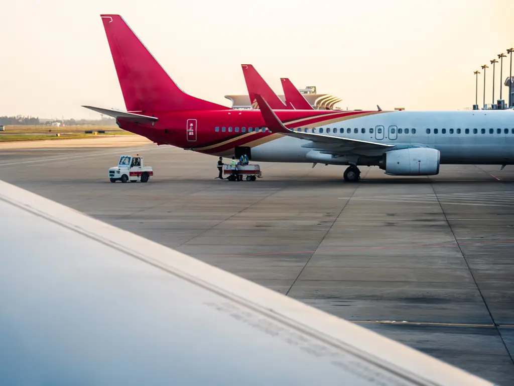 Avião comercial na placa de um aeroporto com equipamento de assistência em terra.