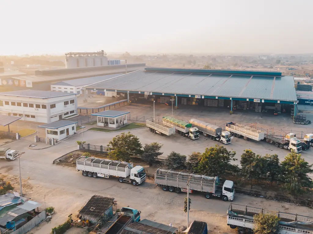 Fleet trucks and commercial vehicles parked at an industrial warehouse facility.
